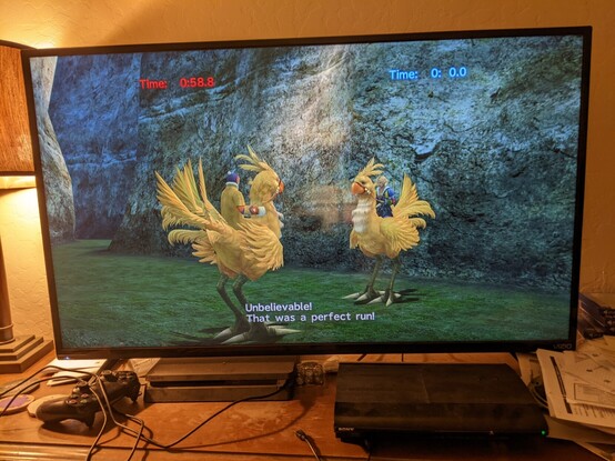 Two racers, the player and a trainer, are mounted on yellow chocobos, facing each other at the end of a race. The player's overall time is 0.0 seconds. The trainer says, "Unbelievable! That was a perfect run!"