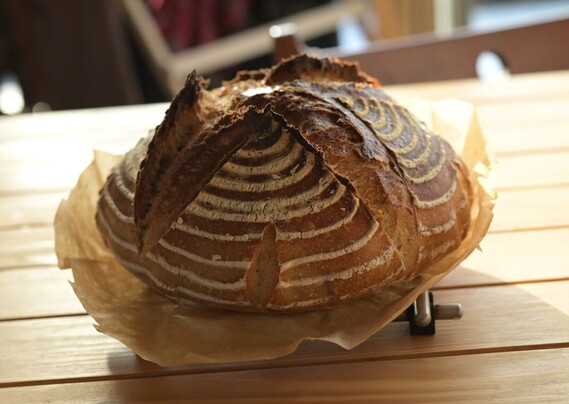A loaf of sourdough bread fresh from the oven, sitting on a table in the morning light.