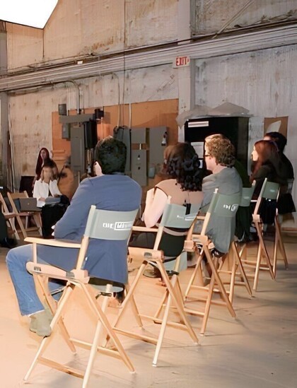 Stars of the Mentalist in a staff meeting sitting on their chairs in a row.