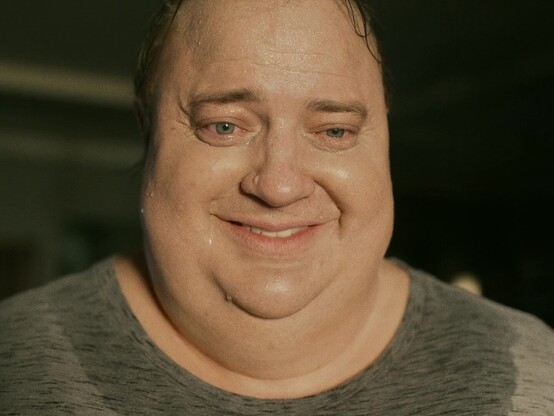 Brendan Frasers Charakter Charlie aus dem Film "The Whale", wie er völlig verschwitzt in die Kamera lächelt.