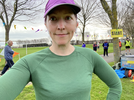 Pale white lady in green running top & purple hat before running 