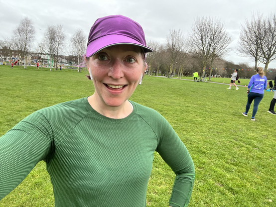 Pale white lady in green running top & purple hat after running 