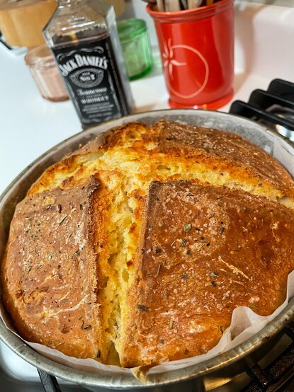 An overhead view of freshly-baked Irish soda bread made from spelt flour, straight out of the oven. A bottle of Jack Daniels is in the background.