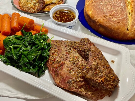 St. Patrick's Day dinner, clockwise, before the carving: potato pancakes, whiskey--mustard dipping sauce, Irish soda bread,  corned beef, sautéed spinach, and cooked carrots.