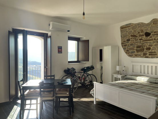 Zwei Räder in einem großen Wohnraum mit Tisch, Bett und Blick in die Berge