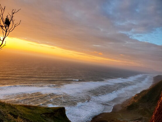 Dusk over the ocean, with a blaze of setting sunlight and foam on the waves.