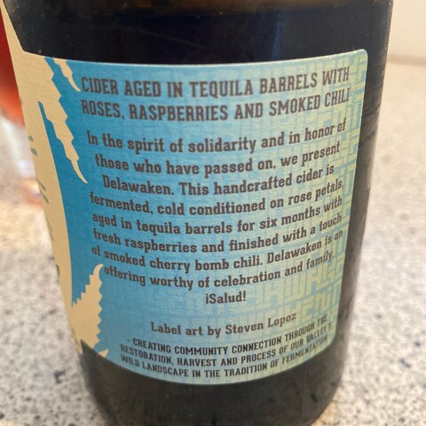 Reverse side of cider label:

CIDER AGED IN TEQUILA BARRELS WITH ROSES, RASPBERRIES AND SMOKED CHILI
In the spirt of solidarity and in honor of those who have passed on, we present Delawaken. This handcrafted cider is fermented, cold conditioned on rose petals, aged in tequila barrels for six months with fresh raspberries and finished with a touch of smoked cherry bomb chili. Delawaken is an offering worthy of celebration and family. 
¡Salud!
Label art by Steven Lopez

CREATING COMMUNITY CONNECTION THROUGH THE RESTORATION, HARVEST AND PROCESS OF OUR VALLEY’S WILD LANDSCAPE IN THE TRADITION OF FERMENTATION. 