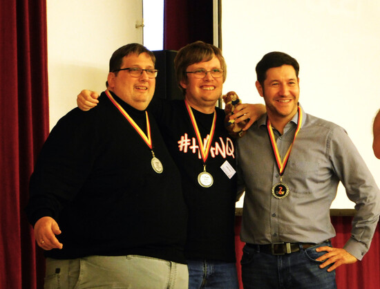 Bei der Siegerehrung der Deutschen Quizmeisterschaft 2023: Markus Müller, Steffen Löwe und Sebastian Jacoby posieren mit ihren Medaillen.