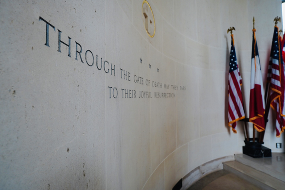 Picture inside the chapel at the American Cemetery in Normandy with ext on the wall and flags on the right of the image. 