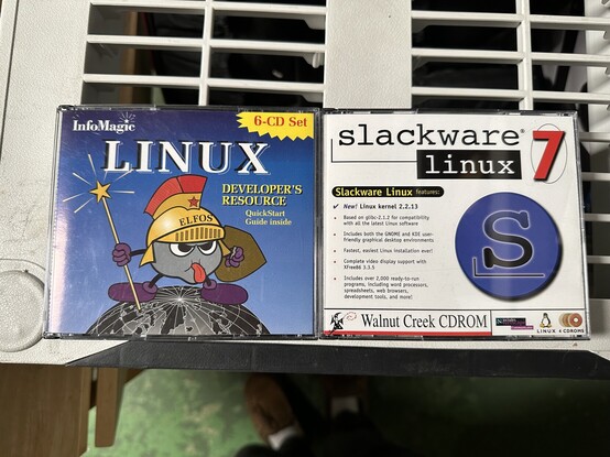 Old CD-ROMs containing Linux distributions. The left one is an InfoMagic distro from 1996, and the right is Slackware 7 from 1999. 