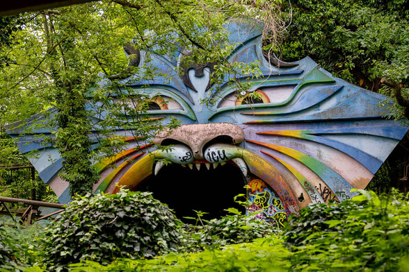 This is a photo of roller-coaster tracks going to the jaws of a psychedelic cat or a baboon or some weird creature at Spreepark, the old abandoned amusement park in Berlin.