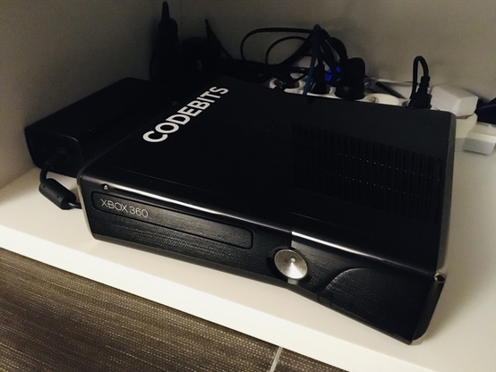 A black XBox360 Slim model, with a vinyl CODEBITS decal on top.