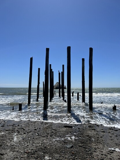 The remains of the pier as it appears today after storms destroyed most of the structure and workers removed the rest. A few remaining piers stand vertically in front of the cement ship.