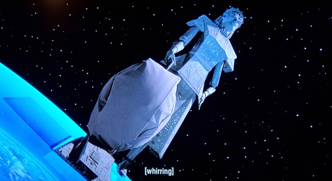 Shot is from the Original Series, season 3, episode Spock's Brain. Pictured is a planet encased in glass, and a enormous looking ship in the shape of a women operating a giant vacuum cleaner that is positioned over an opening in the planet's shield. We call her....

*timpani sounds*

MEGAMAID. 
Closed caption reads, "whirring"
