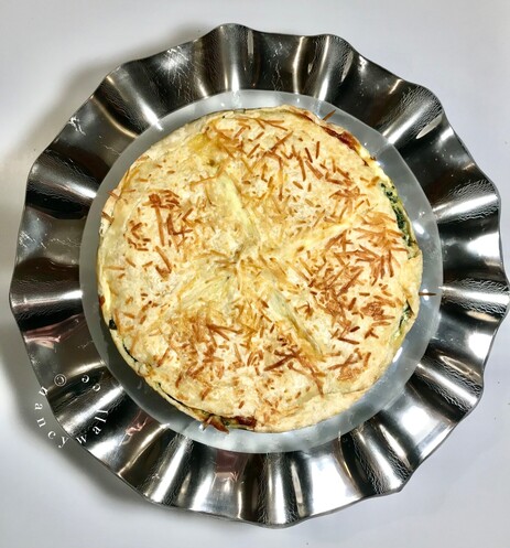 Overhead view of the Torta Pasqualina on a round glass plate with a silver ruffled edge. The plate is crafted by Annie Glass in California.