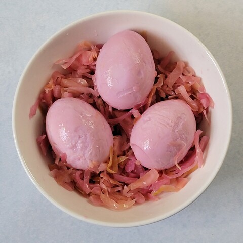 Pink hardboiled eggs (no shell) nestled in a nest of sauerkraut.