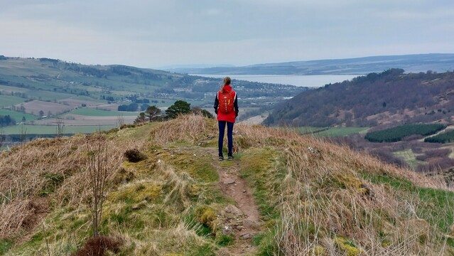 I'm standing on top of a hill, enjoying the fantastic view overlooking Dingwall and the Cromarty Firth. The sky is cloudy. 