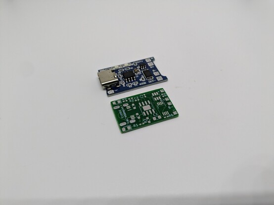 Original TP4050 charging board on top with an unpopulated replacement PCB below it 