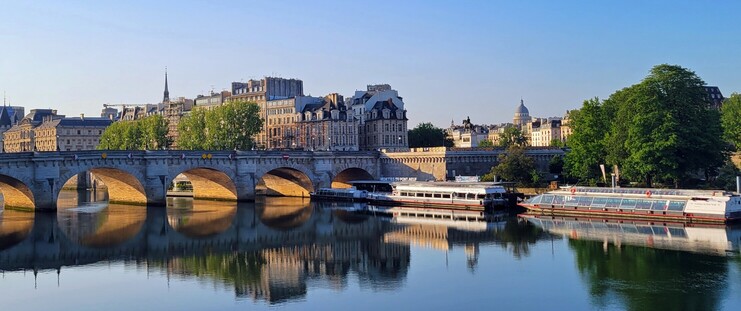 Looking  across the river at a bridge, the conciergerie,and two barges in the early morning light.