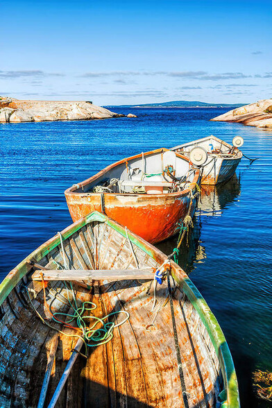 Three colorful paddle wooden fishing boats tide together at Peggy's Cove, Nova Scotia, Atlantic Canada