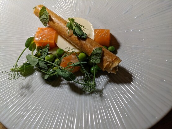 A starter dish of salmon, peas, a roll and panna cota.