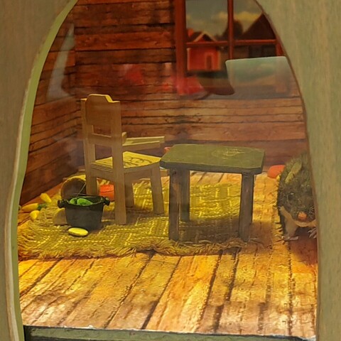 Hirsiseinäiseksi maalaistuvaksi kalustettu hiiren kolo. Hiiri näkyy osittain oikeassa reynassa.