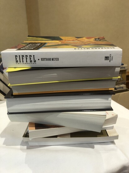 A stack of books with a book about the Eiffel programming language on top.