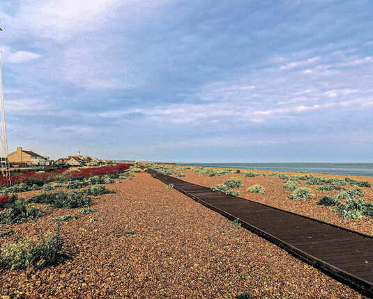 Extreme wide-angle image of Shoreham Boardwalk showing wide landscape with very small Brighton skyline in the background. 