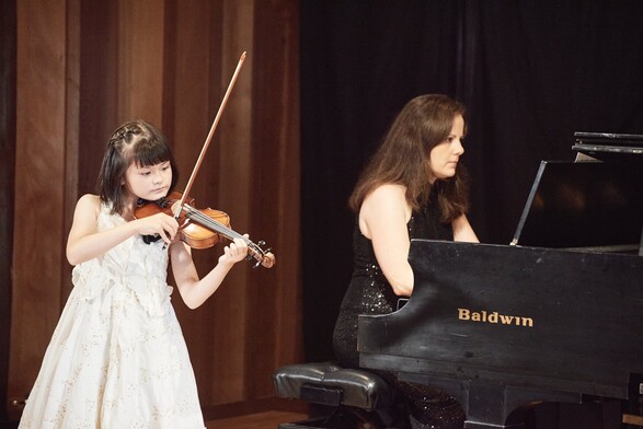 Violin student playing with a piano accompanist - K&M Music School Violin Lessons for Kids and Adults in San Diego. When playing with a piano accompanist, the violinist, and the pianist work together to create a harmonious sound. The pianist provides a supportive and complementary role to the violinist's melody, often playing the chords and harmonies that accompany the violin's main melody. This collaborative performance requires both musicians to listen and communicate with each other, adjusting their playing to match the other's tempo and expression. It can be a rewarding experience for both the performers and the audience.