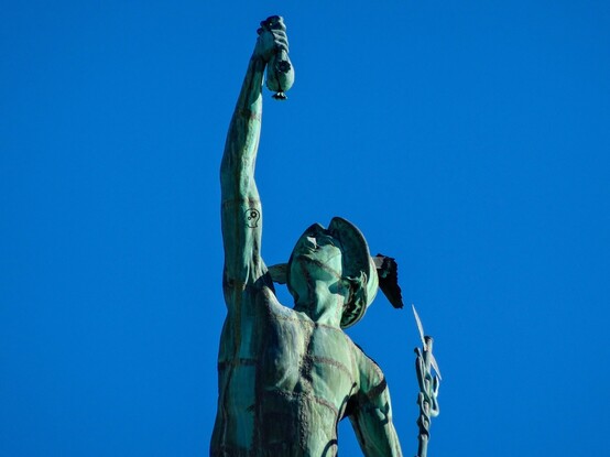 This is a color photograph of a copper statue of Mercury atop the Aqueduct Building in Rochester, New York.