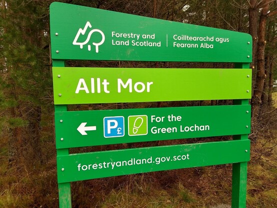 Forestry and Land Scotland sign welcoming people to the Allt Mor car park in Glenmore. Includes the directions "For the Green Lochan".