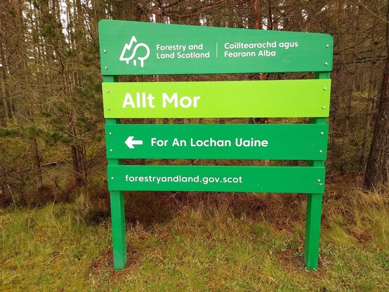 Forestry and Land Scotland sign welcoming people to the Allt Mor car park in Glenmore. Includes the directions "For An Lochan Uaine".