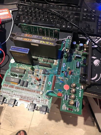 A photo of the Atari 800 board removed from the plastic outer case and metal Faraday cage, with an Asteroids cartridge in the left slot and the 10K ROM and 16K RAM cartridges in the rear slots.
