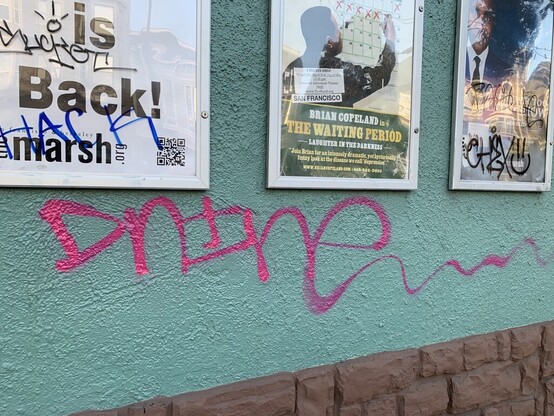 A tagger who wrote "Dnine" in pink spraypaint on a teal wall. The letters are connected, but not really cursive. The word gets bigger as it goes left to right and the tail end of the "e" is really long and exaggerated. It moves up and down as if on a bumpy bus.