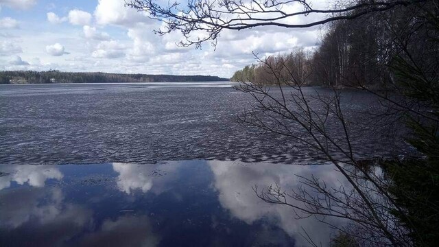 A blue sky and clouds on a surface of a lake that has partly an ice cover 