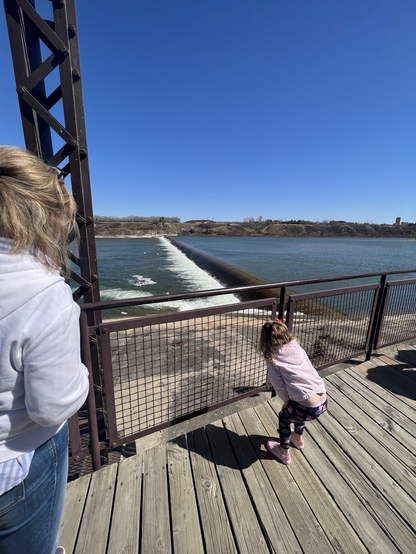 My stepmum and gd looking at the weir on the Saskatchewan River,below a bright blue sky. 