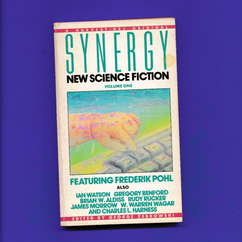 Paperback cover, hand with its index finger pointing to a key on a keyboard against a yellow-green-blue blackground. Handwritten note right across the cover from a literary agent based in Zurich, marking the book as a “sample” for a client.