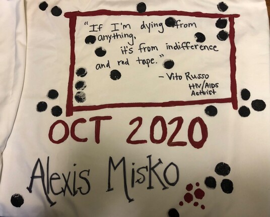 Black inkblots splatter a cream-colored pillow case with a red text box that reads, "If I'm dying from anything, it's from indifference and red tape. - Vito Russo HIV/AIDS Activist” and below in large letters reads:
OCT 2020
Alexis Misko