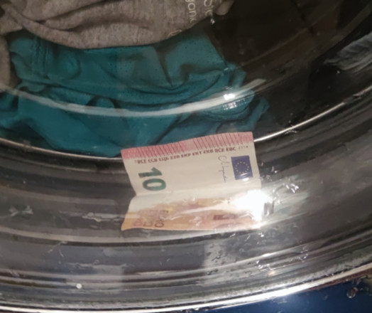 In der Waschmaschine ist nach dem Waschgang ein mitgewaschener 10€-Schein durch die Tür zu sehen. 