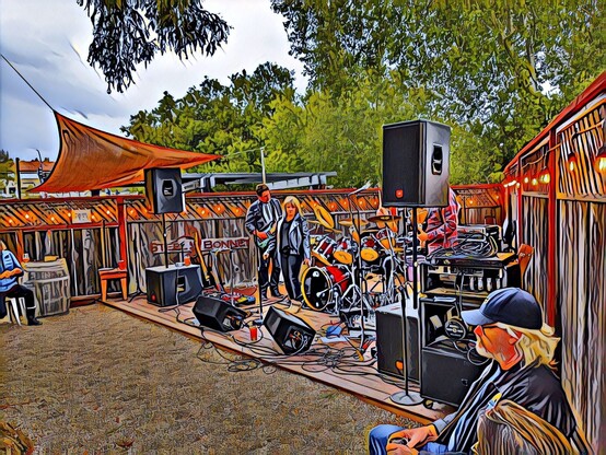 A band on an outside stage. Photo has a filter on it to make it look like a painting.
