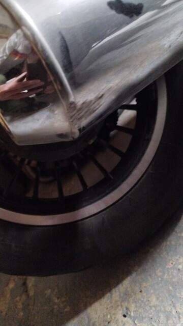A motorcycle exhaust that has been scratched on the ground in a corner 