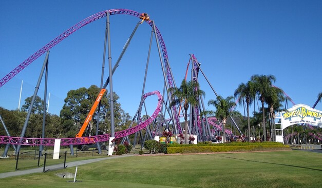 Warner Bros MovieWorld park entrance with a roller coaster ride being serviced by a truck-mounted crane.