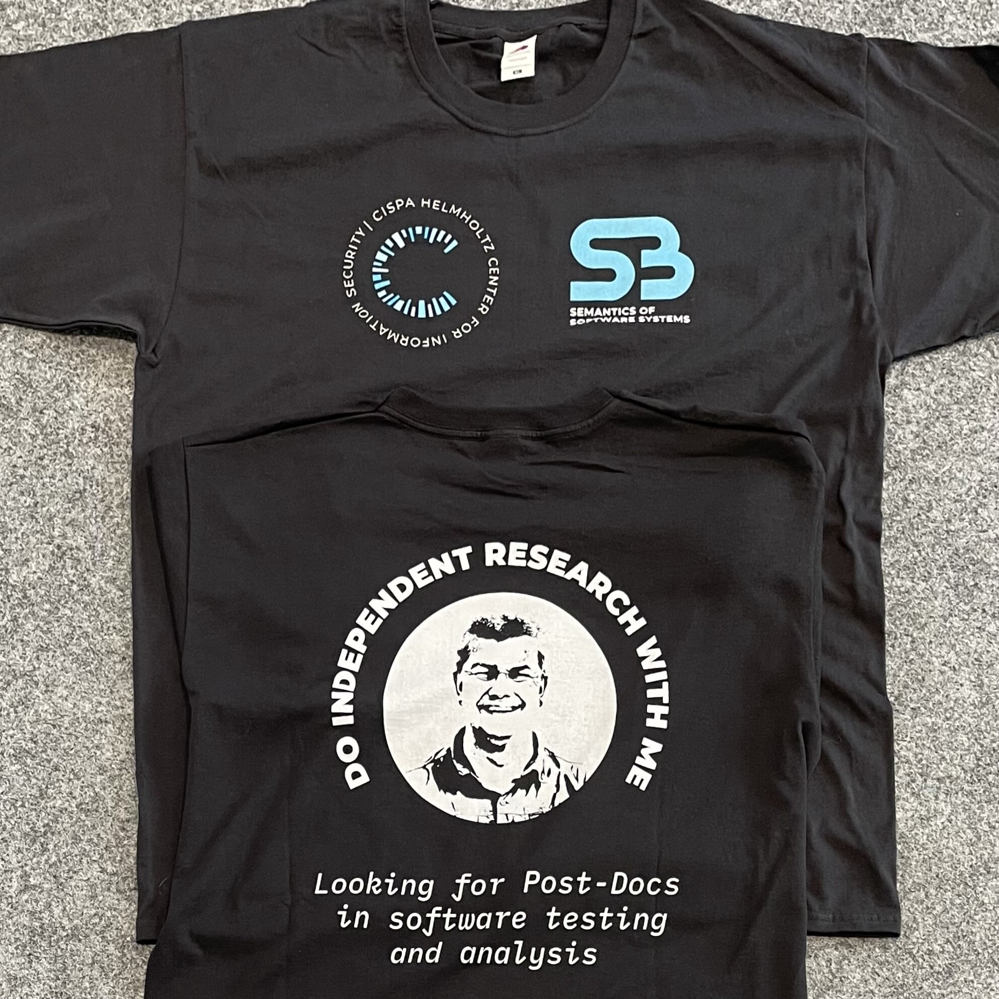 A black T-shirt, front and back. Front shows logos from @CISPA and #S3; the back shows “Looking for Post-Docs in software testing and analysis” and a photo of @AndreasZeller, surrounded by the words “Do independent research with me”