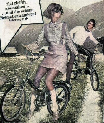 Freizeitvorschläge aus der Werbeabteilung. 2 Bekloppte auf lächerlichen Fahrrädern vor Alpenpanorama