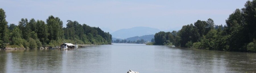 Looking up a smooth tree-lined river toward the looming hills in the distance.