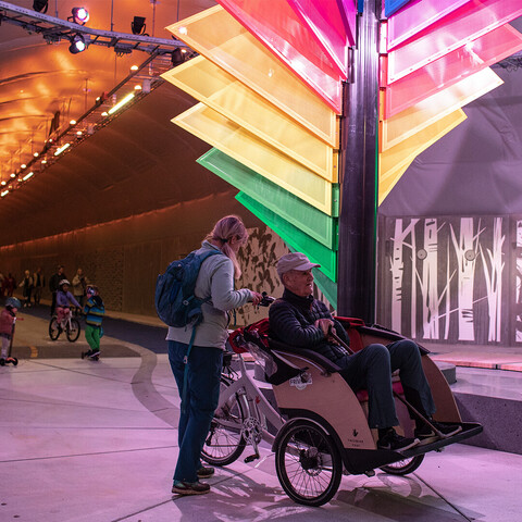 Radfahrende fahren durch den neuen Fahrradtunnel in Bergen. Im Zentrum steht die große Sonnenuhr in der Mitte des Tunnels.