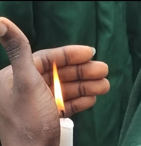 Student shading a candle flame with his palm.