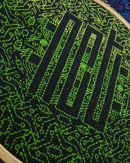 Detail of the gradient green embroidered NCT against black linen.