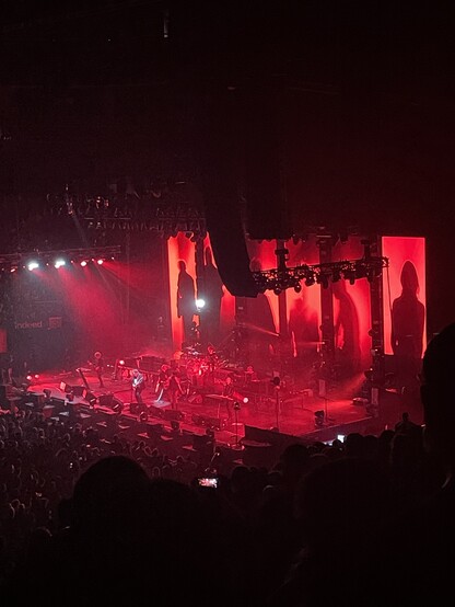 The Cure performing on stage bathed in red mood lighting 