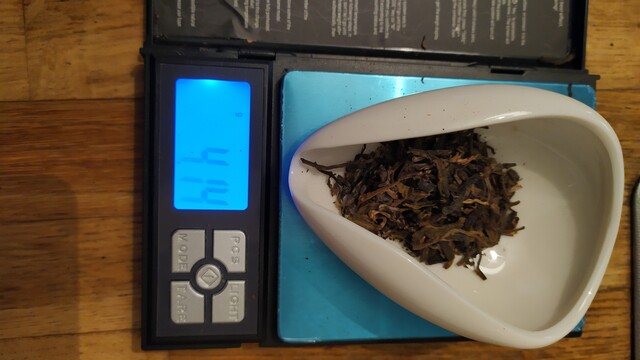 Tea leaves on a white chahe (presentation vessel) on a precision scale, showing 4,14g